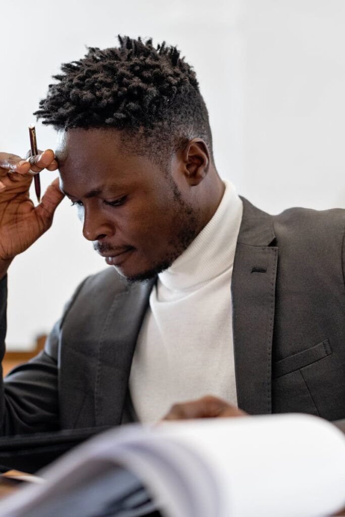 pexels photo 8729951 8729951 A focused businessman in a suit examines documents while deep in thought in an office setting.